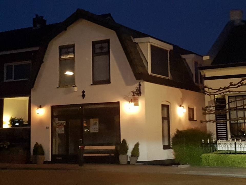 Het witte huis van Skinsation aan de Hoefweg in de avond, met verlichte ramen